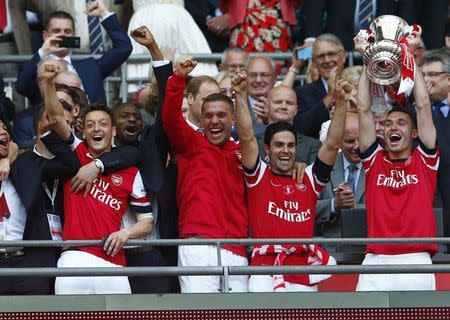 Arsenal's Thomas Vermaelen (R) lifts the trophy as he celebrates with theam mates after winning their FA Cup final against Hull City, at Wembley Stadium in London, May 17, 2014. REUTERS/Eddie Keogh