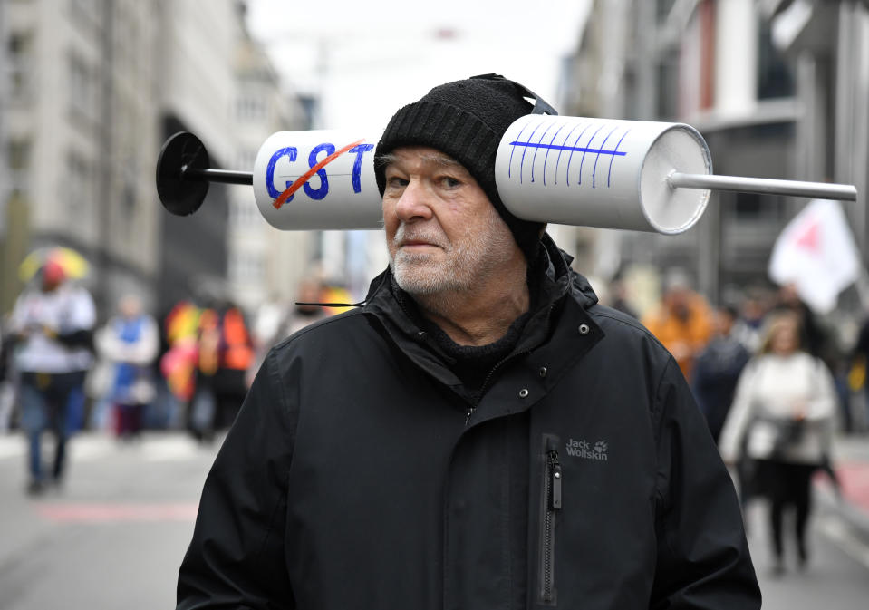 A protestor marches with a syringe costume during a demonstration against COVID-19 measures in Brussels, Sunday, Jan. 23, 2022. Demonstrators gathered in the Belgian capital to protest what they regard as overly extreme measures by the government to fight the COVID-19 pandemic, including a vaccine pass regulating access to certain places and activities and possible compulsory vaccines.(AP Photo/Geert Vanden Wijngaert)