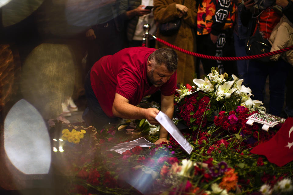 A man places flowers and photographs in the memorial spot of Sunday's explosion on Istanbul's popular pedestrian Istiklal Avenue in Istanbul, Turkey, Monday, Nov. 14, 2022. Turkish police said Monday they have detained a Syrian woman with suspected links to Kurdish militants and that she confessed to planting a bomb that exploded on a bustling pedestrian avenue in Istanbul, killing six people and wounding several dozen others. (AP Photo/Francisco Seco)