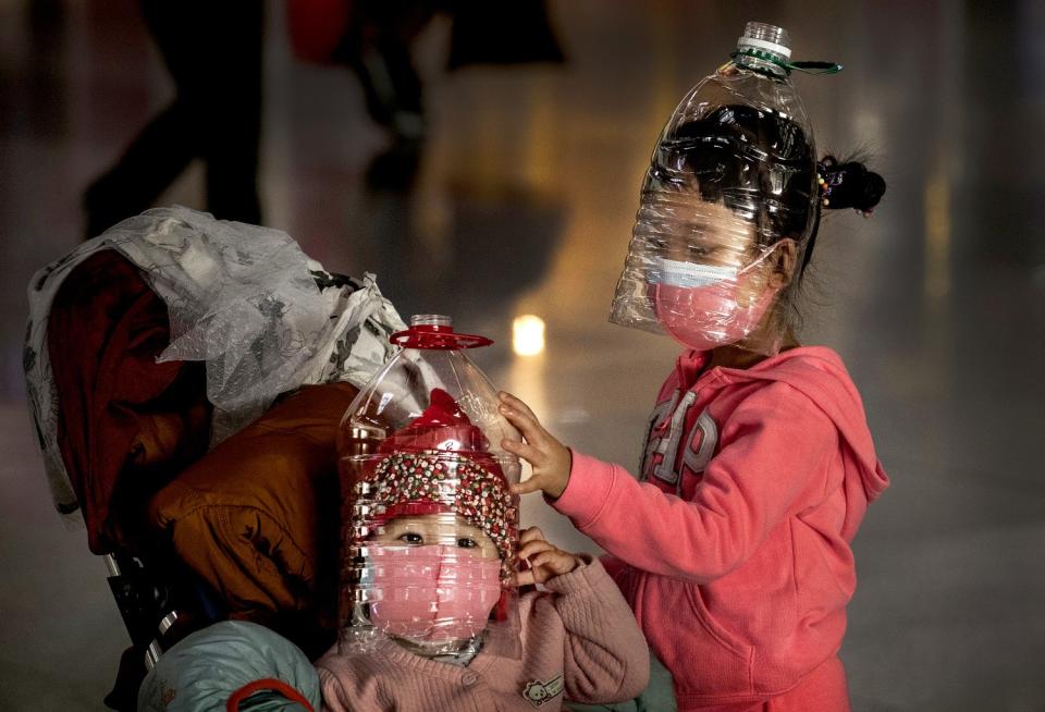 CHINA: Chinese children wear masks and plastic bottles over their faces as protection against the coronavirus while waiting to check in to a flight at Beijing Capital International Airport.