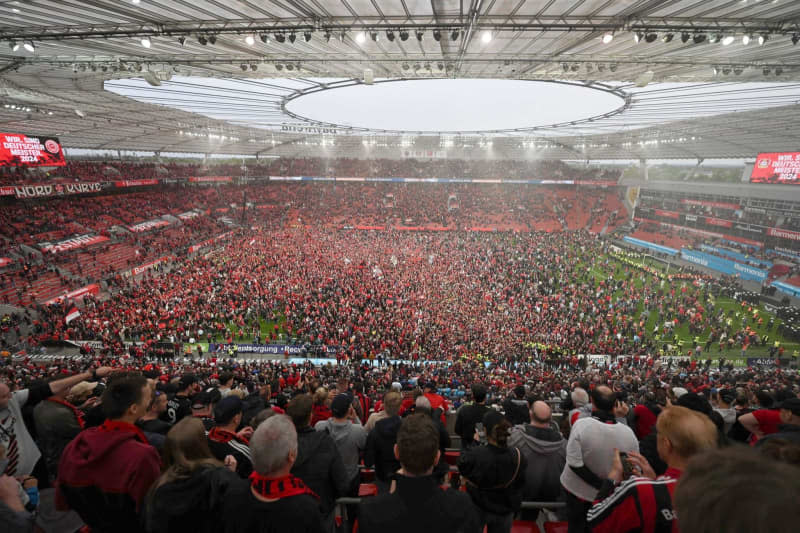 Leverkusen fans run onto the pitch to celebrate winning the German championship following the German Bundesliga soccer match between Bayer 04 Leverkusen and SV Werder Bremen at BayArena. David Inderlied/dpa