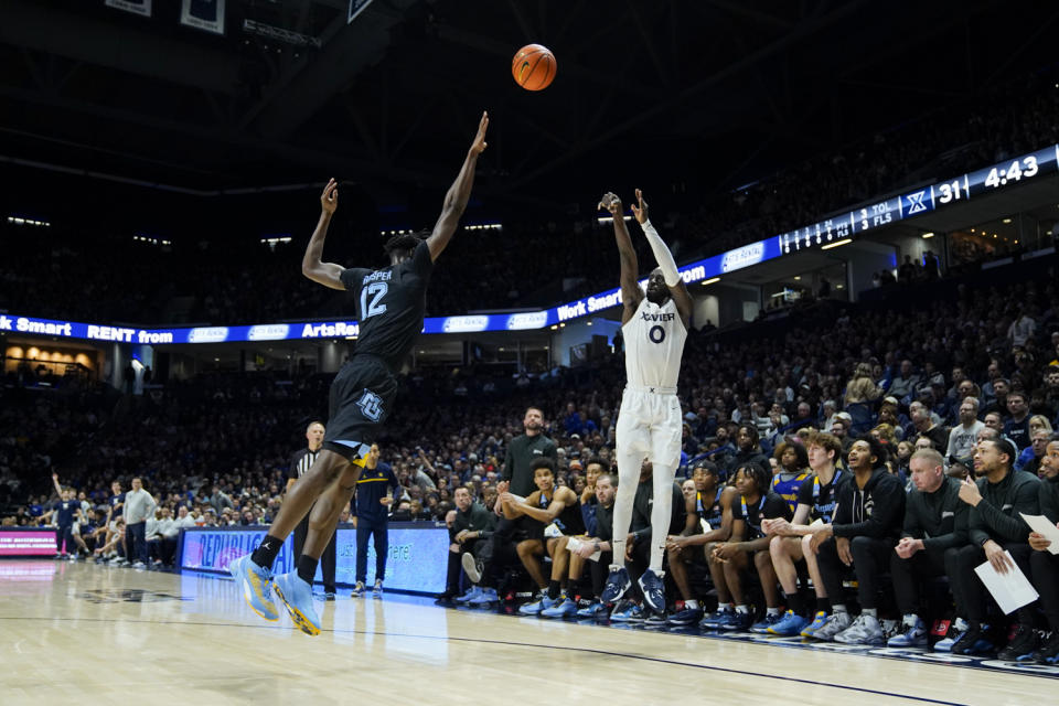 Xavier guard Souley Boum (0) shoots against Marquette's Olivier-Maxence Prosper (12) during the first half of an NCAA college basketball game, Sunday, Jan. 15, 2023, in Cincinnati. (AP Photo/Jeff Dean)