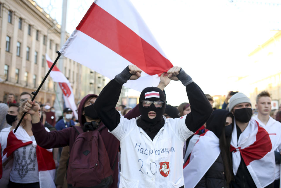 A masked protester gestures in front of police blocking the road to prevent against an opposition rally to protest the official presidential election results in Minsk, Belarus, Sunday, Sept. 20, 2020. Tens of thousands of Belarusians calling for the authoritarian president to resign marched through the capital on Sunday as the country's wave of protests entered its seventh week. Hundreds of soldiers blocked off the center of Minsk, deploying water cannon and armored personnel carriers and erecting barbed wire barriers. (AP Photo/TUT.by)