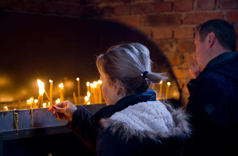 In this Sunday, March 17, 2019 photo, a woman lights a candle at an Orthodox church in the Bosnian Serb wartime stronghold of Pale, Bosnia-Herzegovina. Nearly a quarter of a century since Bosnia's devastating war ended, former Bosnian Serb leader Radovan Karadzic is set to hear the final judgment on whether he can be held criminally responsible for unleashing a wave of murder and mistreatment by his administration's forces. United Nations appeals judges on Wednesday March 20, 2019 will decide whether to uphold or overturn Karadzic's 2016 convictions for genocide, crimes against humanity and war crimes and his 40-year sentence. (AP Photo/Darko Bandic)