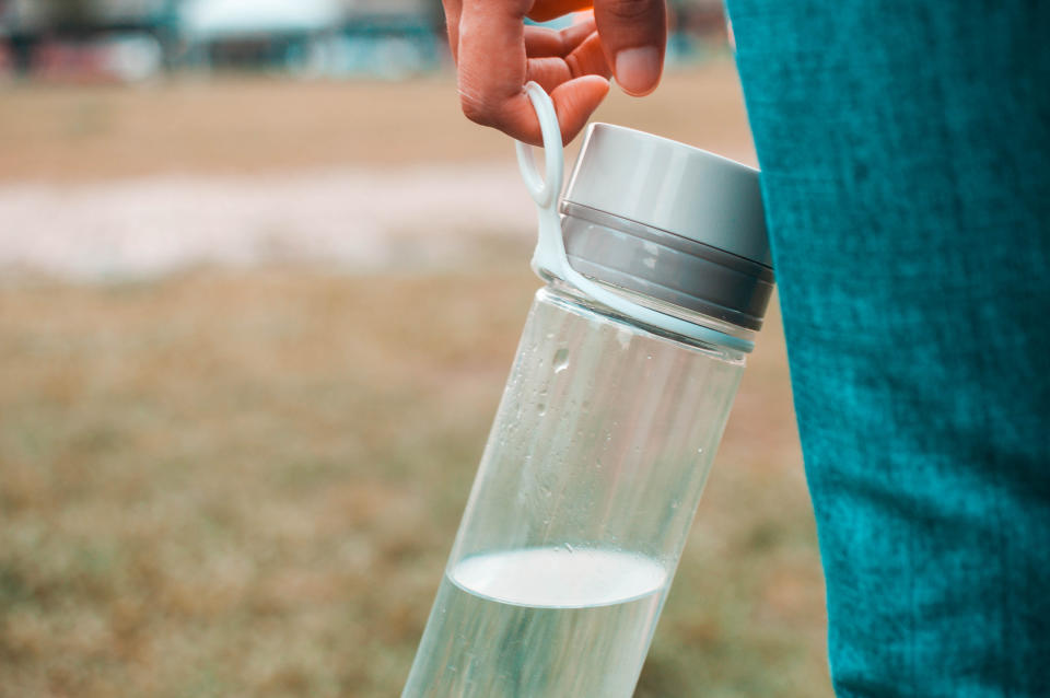 a person holding a reusable water bottle by their side