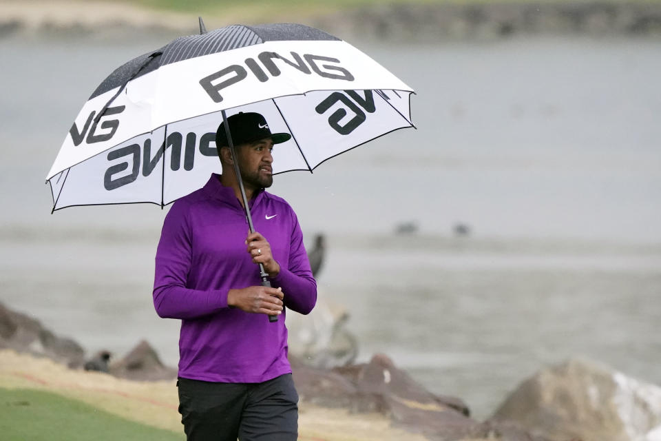 Tony Finau carries an umbrella in the rain on the 18th fairway during the third round of The American Express golf tournament on the Pete Dye Stadium Course at PGA West, Saturday, Jan. 23, 2021, in La Quinta, Calif. (AP Photo/Marcio Jose Sanchez)