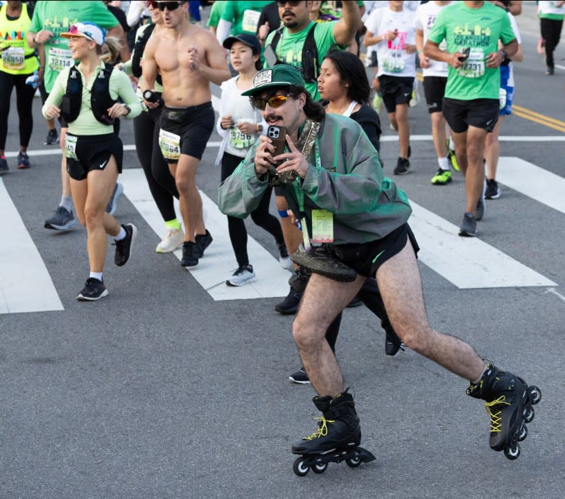 LOS ANGELES, CA MARCH 17: A rollerblader records the festivities in Chinatown during the LA Marathon on Sunday, March 17, 2024. Over 25,000 runners competed this year. (Myung J. Chun / Los Angeles Times via Getty Images)
