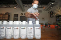 Chainbridge Distillery owner Bela Nahori displays bottles of hand sanitizer in Oakland Park on Tuesday, Aug. 11, 2020. The local distillery was given FDA approval to stop making spirits and instead make hand sanitizer at the start of the pandemic, but the demand has since plummeted and Nahori is currently overstocked. (John McCall /South Florida Sun-Sentinel via AP)