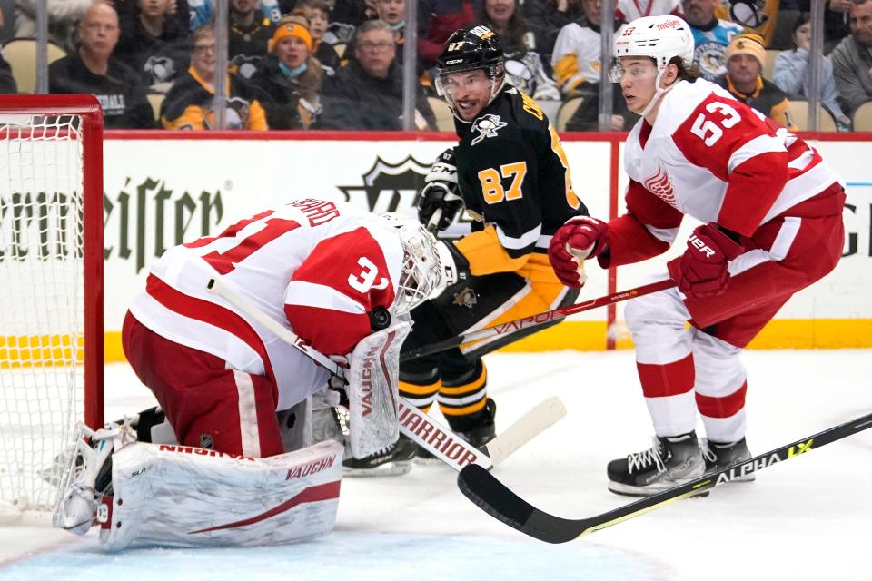 Detroit Red Wings goaltender Calvin Pickard (31) stops a shot by Pittsburgh Penguins' Sidney Crosby (87) with Moritz Seider (53) defending during the second period of an NHL hockey game in Pittsburgh, Friday, Jan. 28, 2022.