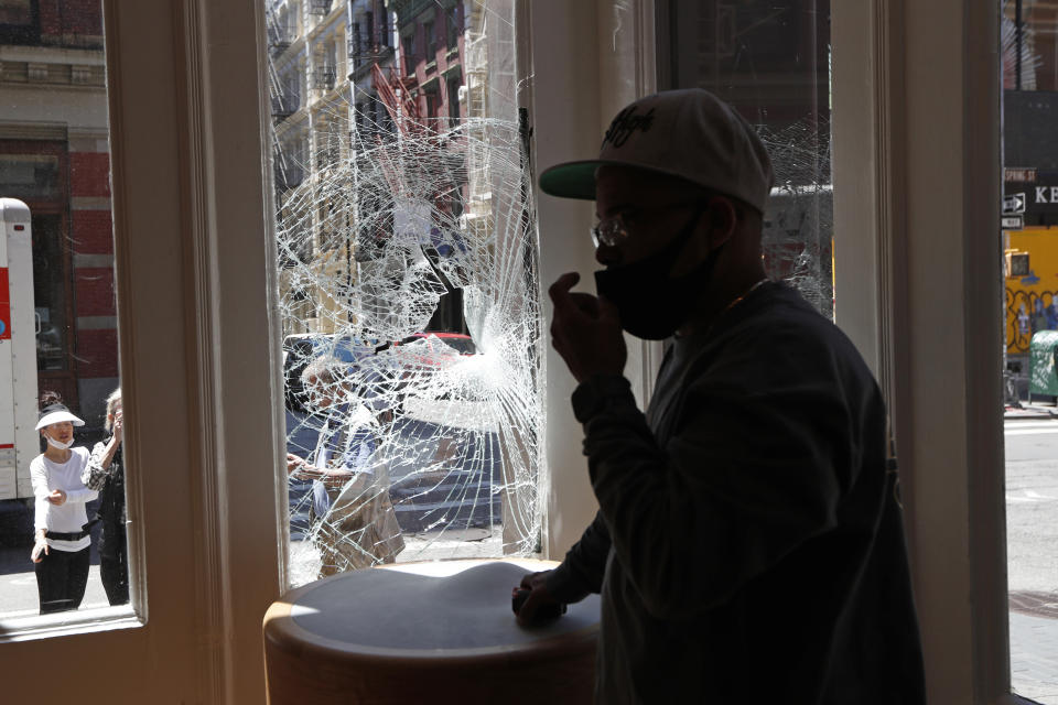 A glass installer adjusts his face protection mask before installing plywood over the broken windows of a Bang and Olafson store, Sunday, May 31, 2020, in the trendy SoHo neighborhood of New York, which was vandalized during protests over the death of George Floyd Saturday night. Floyd died Memorial Day in Minneapolis while in police custody. (AP Photo/Kathy Willens)
