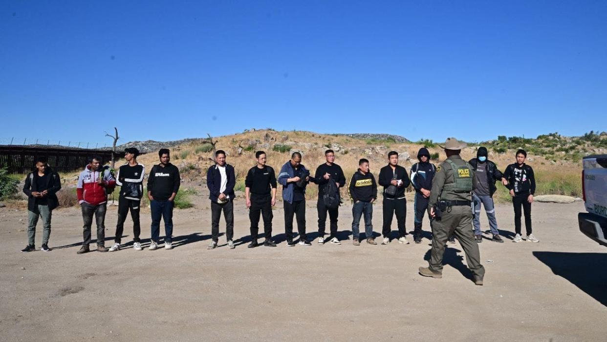 border officer with line of Chinese migrants on road