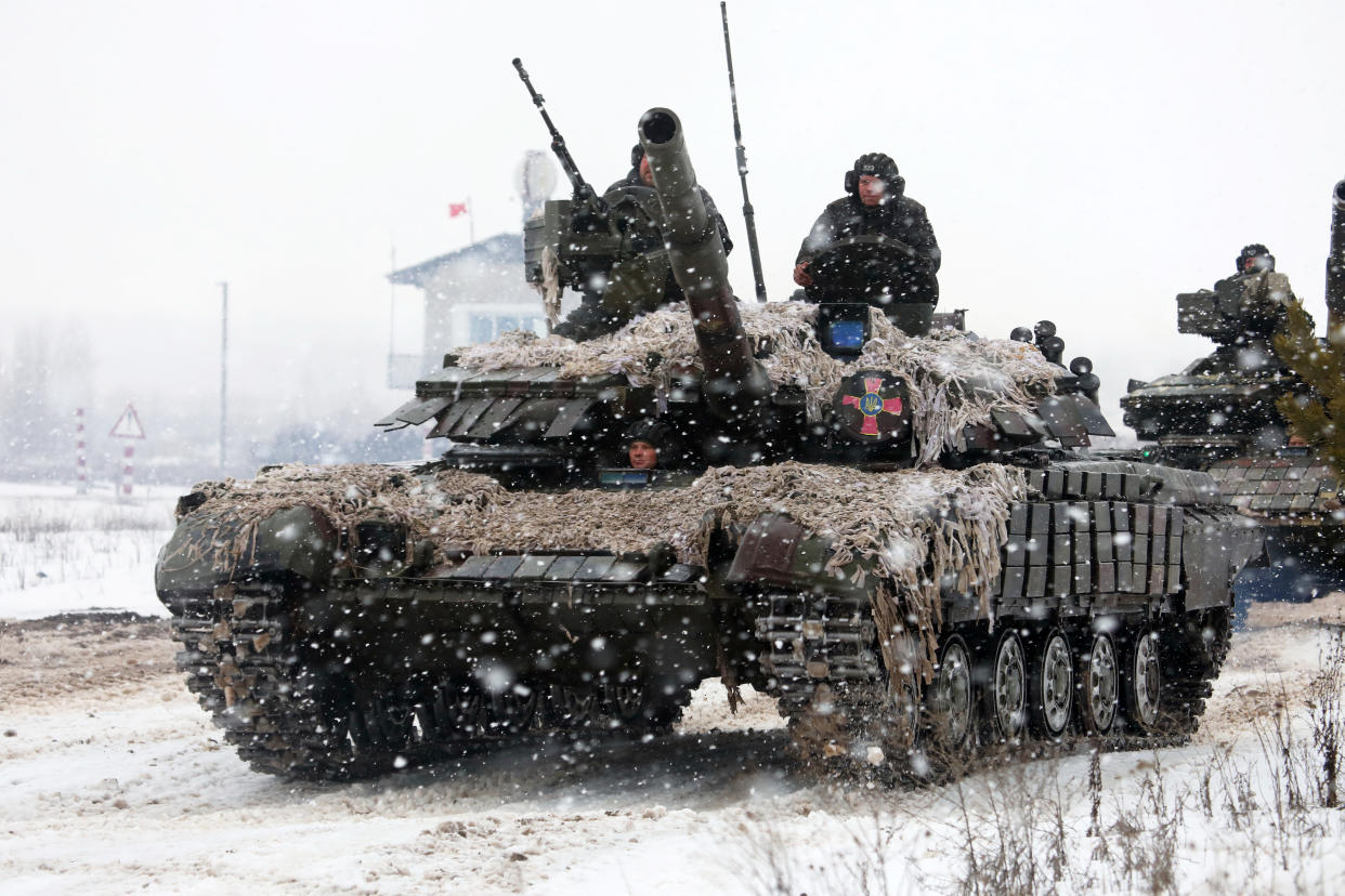 Soldiers ride on tanks during a snowfall.