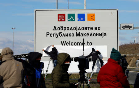 Workers cover a sign of the Republic of Macedonia at the border between Macedonia and Greece, near Gevgelija, Macedonia February 13, 2019. REUTERS/Ognen Teofilovski