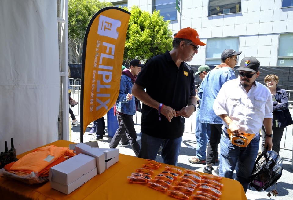 In this photo taken Friday, June 21, 2019, FlipTix CEO Jaime Siegel, left, explains what his company does at the entrance of the Clusterfest comedy event in San Francisco. The company's application lets people who leave a venue early sell their ticket and lets someone who wants the remainder of the ticket buy it. (AP Photo/Eric Risberg)