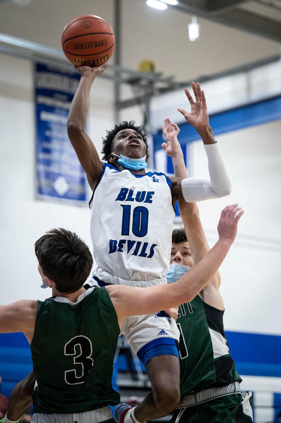 Leominster's Warren Acceus shoots over Wachusett's Tucker McDonald and Adam Bates.