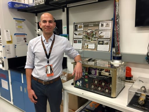 NASA scientist Charles Malespin poses next to a reproduction of the SAM instrument aboard the rover Curiosity on Mars