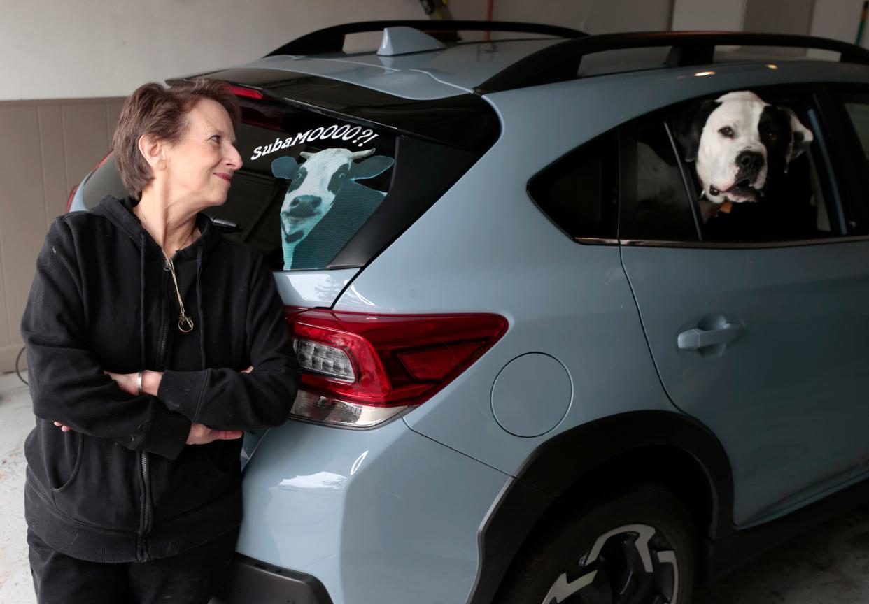 Pamela Pitlanish of Clinton Township with her 2021 Subaru Crosstrek and her dog Deebo at her home on Tuesday, December 5, 2023. Pitlanish is a member of the Moo Moo Subaru Facebook group. 
The group has members who love their Subarus and place small rubber cows on Subarus that they see out in public. It’s something similar that Jeep owners do with rubber duckies that can often be seen on the dashboards of their Jeeps. Pitlanish does a cow keychain that she puts around the driver-side door handles of various Subarus.