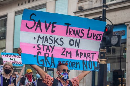 <span class="caption">Protester holding a transgender flag sign encouraging social distancing at Trans Pride 2020 in London.</span> <span class="attribution"><a class="link " href="https://www.shutterstock.com/image-photo/londonengland-12-september-2020-protester-holding-1818443345" rel="nofollow noopener" target="_blank" data-ylk="slk:JessicaGirvan/Shutterstock;elm:context_link;itc:0;sec:content-canvas">JessicaGirvan/Shutterstock</a></span>