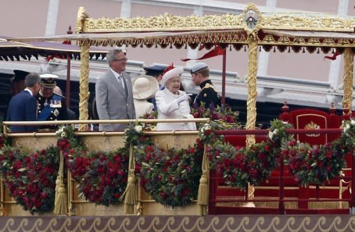 Britain's Queen Elizabeth II (centre) gestures aboard the royal barge 'Spirit of Chartwell' during the Thames Diamond Jubilee Pageant on the River Thames in London on June 3, 2012