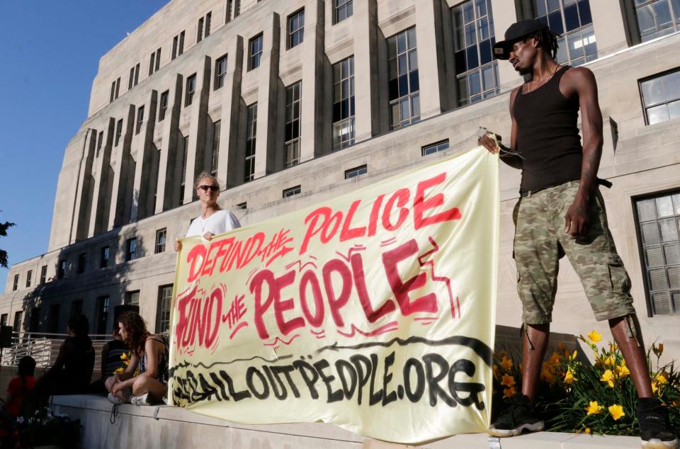 Protesters hold a banner wanting to defund police and then fund people during the protest against ICE, Friday, July 10, 2020, in Sheboygan, Wis.