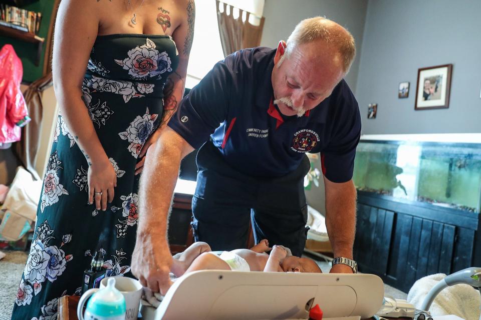 Project Swaddle community paramedic Darren Forman measures 7-month-old Easton Mings as the baby's mother Chloe Mings (left) looks on Wednesday, Aug. 7, 2019, at her Crawfordsville home in Montgomery County, Indiana. Montgomery County is one of the obstetric deserts in Indiana.