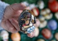 German pensioner Christa Kraft displays a colourful hand-painted Easter egg before she decorates an apple tree in the garden of her summerhouse, in the eastern German town of Saalfeld, March 19, 2014. Each year since 1965 Volker and his wife Christa spend up to two weeks decorating the apple tree with their collection of 10,000 colourful hand-painted Easter eggs in time for Easter celebrations. REUTERS/Fabrizio Bensch