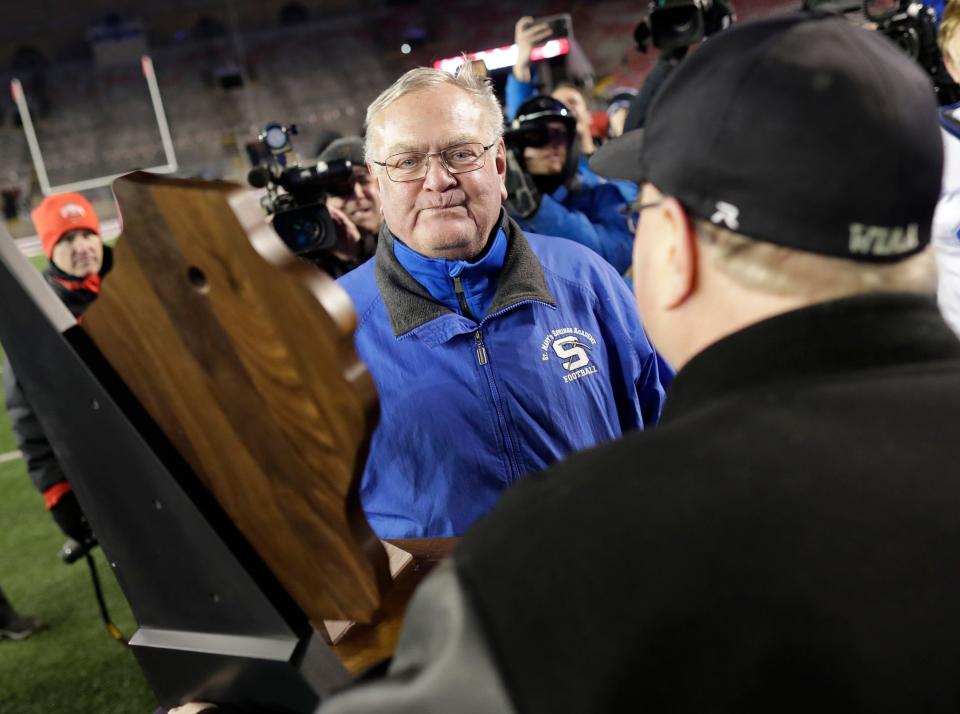 St. Mary's Springs Academy head coach Bob Hyland accepts the championship trophy after the Ledgers defeated Stratford High School during the WIAA Division  5 state championship football game on Thursday, November 15, 2018, at Camp Randall in Madison, Wis.