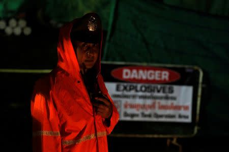 A police officer stands guard in the rain, outside Tham Luang cave complex, where 12 schoolboys and their soccer coach are trapped inside a flooded cave, in the northern province of Chiang Rai, Thailand, July 7, 2018. REUTERS/Tyrone Siu