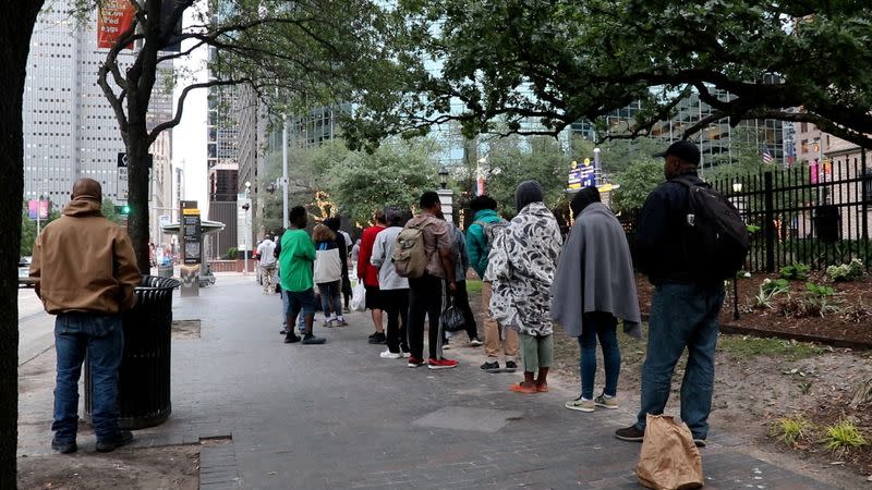 People line up for donated meals near the Houston Central Library, where the city is enforcing a law restricting the feeding of groups in public