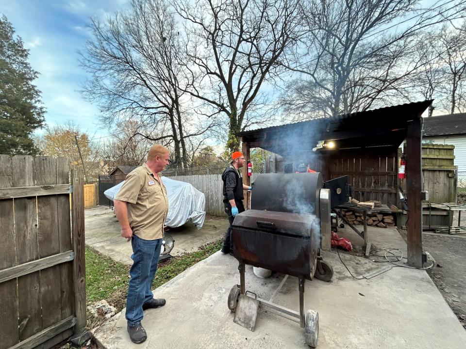 Owner Jeff Roy and his son Dustin Roy work the smokers behind Roy Meat Service on Dec. 7, 2023. The owner of the property behind the store says this concrete slab and shed encroach on the property line and is suing Jeff Roy.