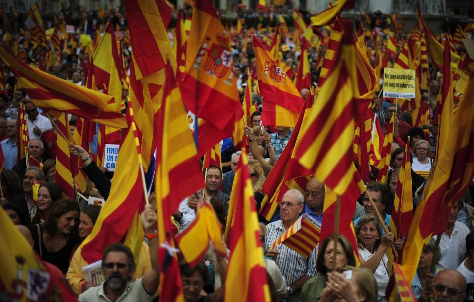 People opposed to the independence of Catalonia hold Catalan and Spanish flags during the holiday known as Dia de la Hispanidad, Spain's National Day in Barcelona, Spain, Friday, Oct. 12, 2012. Spain is observing its National Day festivities in somber mood as the traditional military pageant was scaled back to cut costs. Spain is in recession and under pressure to fix its finances while celebrating the day Christopher Columbus discovered America in the name of the Spanish Crown. (AP Photo/Manu Fernandez)