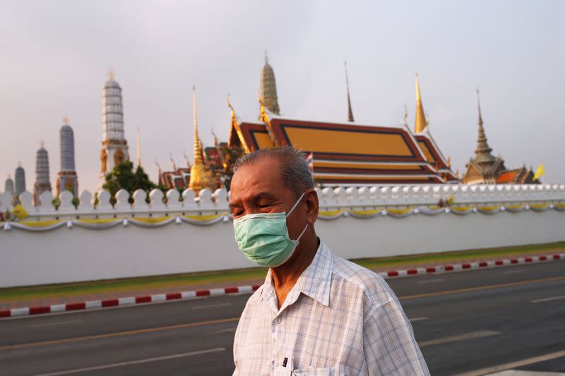 A man wears a mask to prevent the spread of the new coronavirus as he walks near the Grand Palace at Bangkok