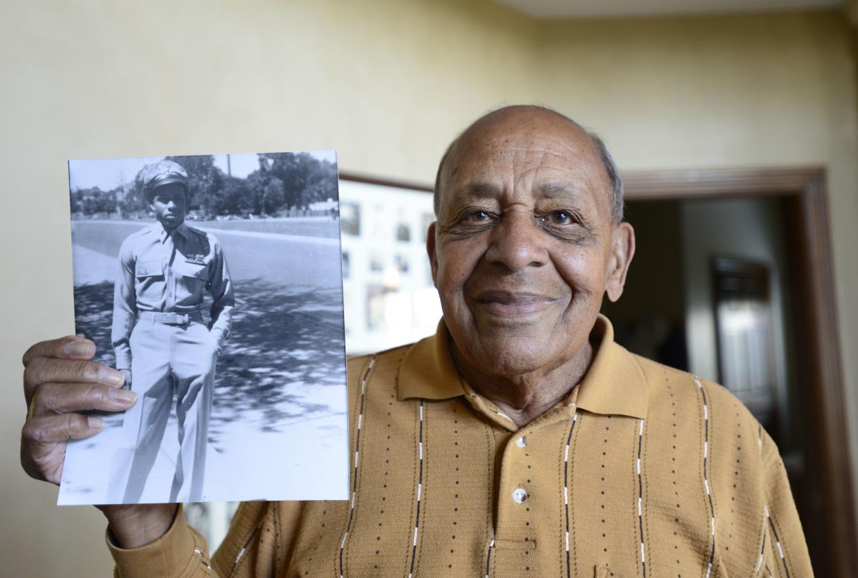 Harold  Brown, a  Tuskegee Airman, holds a picture in 2019 of himself at 20 years old after he returned home from World War II.