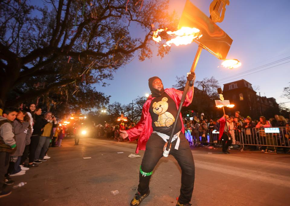 A flambeaux carrier lights the way as the Krewe of Orpheus rolls on the Uptown route with the theme "Glacial Tomes and Conflagrations" in New Orleans on Monday, Feb. 28, 2022. (Brett Duke/The Times-Picayune/The New Orleans Advocate via AP)