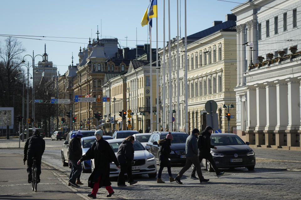 People cross the city street in Helsinki, Finland, Monday, April 3, 2023. NATO Secretary-General Jens Stoltenberg said Monday Finland will become the 31st member of the world's biggest military alliance on Tuesday, prompting a warning from Russia that it would bolster its defenses near their joint border if NATO deploys any troops in its new member. (AP Photo/Sergei Grits)