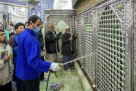 In this Monday, Feb. 24, 2020, photo, a man disinfects the shrine of Saint Masoumeh against coronavirus in the city of Qom 78 miles (125 kilometers) south of the capital Tehran, Iran. Iran's government said Monday that 12 people had died nationwide from the new coronavirus, rejecting claims of a much higher death toll of 50 by a lawmaker from the city of Qom that has been at the epicenter of the virus in the country. (Ahmad Zohrabi/ISNA via AP)
