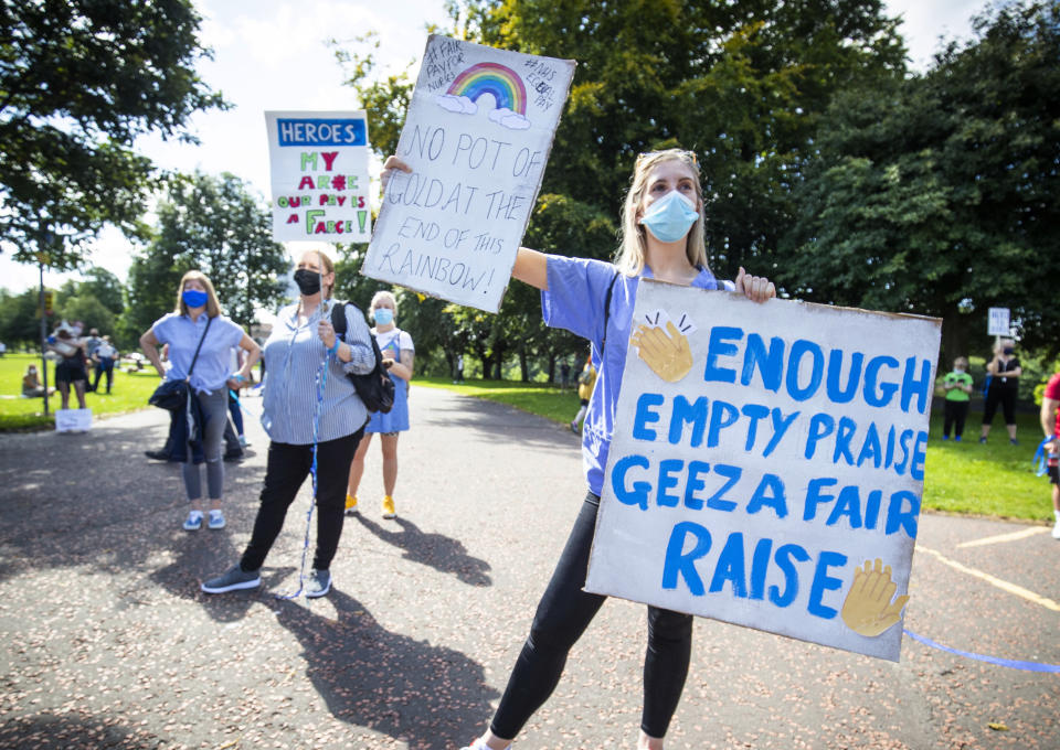 National Health Service (NHS) worker poses with a placards, during a socially distanced demonstration as part of a national protest over pay, in Glasgow, Scotland, Saturday Aug. 8, 2020. Nationwide protests on Saturday are calling for government to address what they claim is many years of reduced wages, and are calling for a voice in plans for public sector pay increases. (Dominic Lipinski/PA via AP)