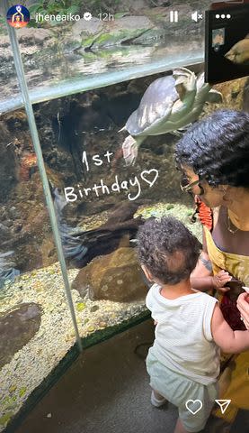 <p>Jhene Aiko/Instagram</p> Jhene Aiko looks at fish at aquarium with son Noah on his first birthday