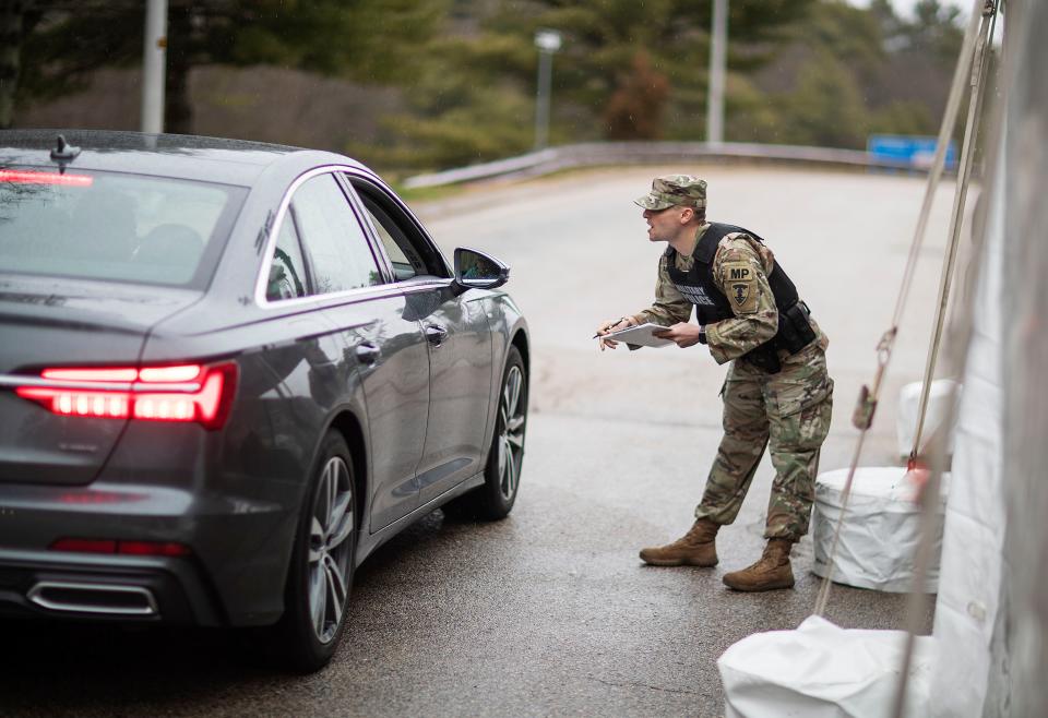 A member of the Rhode Island National Guard Military Police stops car with New York license plates at an I-95 checkpoint in Hope Valley, R.I. on March 28, 2020.