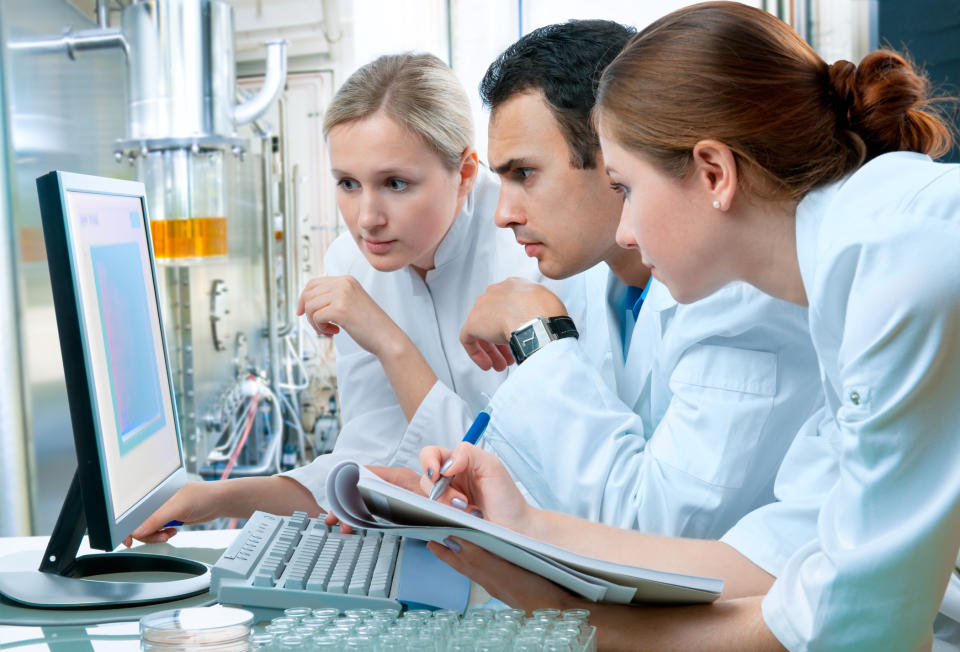 A group of young professionals staring intently at a shared computer screen.