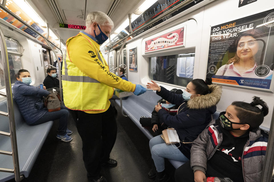 Patrick Foye, Chairman and CEO of the Metropolitan Transportation Authority, hands out face masks on a New York subway, Tuesday, Nov. 17, 2020. He announced at a news conference a regional 'Mask Force' that encourages universal mask usage on public transit. (AP Photo/Mark Lennihan)