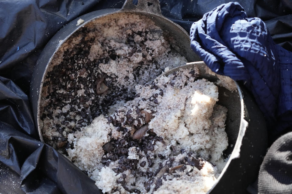 A container with beans and rice lies abandoned in recently arrived rustic migrant boat, Wednesday, Jan. 4, 2023, in Islamorada, Fla. More than 500 Cuban immigrants have come ashore in the Florida Keys since the weekend, the latest in a large and increasing number who are fleeing the communist island. (AP Photo/Wilfredo Lee)