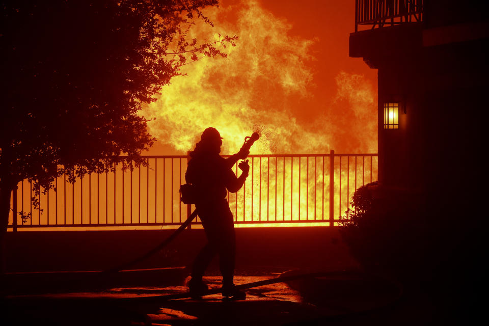 In this Thursday, Oct. 10, 2019 photo, a firefighter waits for water as the Saddleridge fire flares up near homes in Sylmar, Calif. (Photo: Michael Owen Baker/AP)