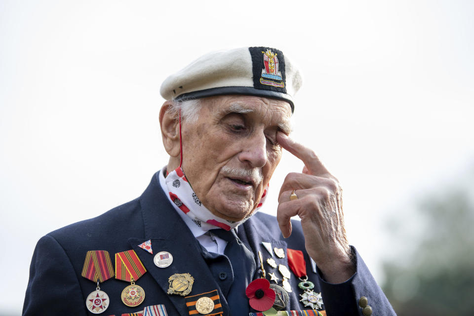 Seymour 'Bill' Taylor, 95, from Colchester, who served as an Able Seaman in the Royal Navy onboard HMS Emerald during the D-Day landings joins neighbours in the street to observe the two minutes silence to pay his respects on Remembrance Sunday, in Essex, England, Sunday, Nov. 8, 2020. (Joe Giddens/PA via AP)