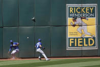 An RBI-double hit by Oakland Athletics' Mark Canha falls between Kansas City Royals center fielder Michael A. Taylor, left, and left fielder Andrew Benintendi during the sixth inning of a baseball game in Oakland, Calif., Sunday, June 13, 2021. (AP Photo/Jeff Chiu)