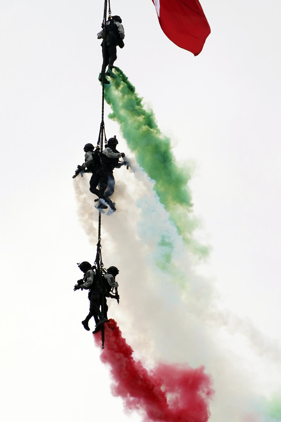 Special forces hang from a helicopter with billowing smoke in the colors of the Mexican flag during the annual Independence Day military parade at the main square, the Zocalo, in Mexico City, Friday, Sept. 16, 2022. (AP Photo/Marco Ugarte)