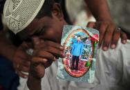 Aziz Ahmed, father of Asif Aziz who was killed in the garment factory fire holds his son's picture in Karachi