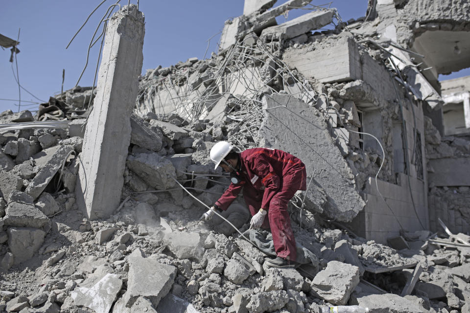 A rescue worker uncovers the body of a detainee from under the rubble of a Houthi-held detention center destroyed by Saudi-led airstrikes in Dhamar, Yemen, Sunday, Sept. 1, 2019. Yemeni officials say airstrikes by the Saudi-led coalition hit a detention center in the southwestern Dhamar province, killing at least 60 people. The officials say the airstrikes took place Sunday and targeted a college in the city of Dhamar, which the Houthi rebels use as a detention center. (AP Photo/Hani Mohammed)