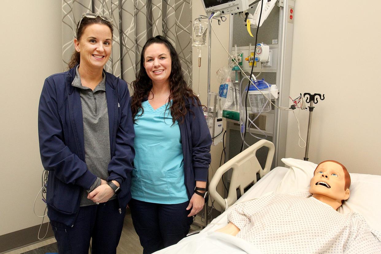 Amanda Larry, left, of Rock Falls, stands next to her sister Ashleigh Chapman, of Sterling, simulation hospital at Highland Community College in Freeport. The sisters graduated together with degrees in nursing at the college's spring graduation ceremony.