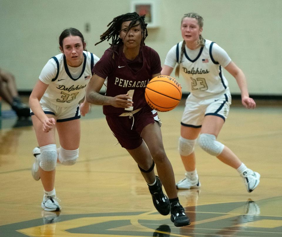 Pensacola High School's Ter'koiyah Long (No. 1) drives down the court while Gulf Breeze's Madison Coughlin (no. 33) and Lila Jacobs (No. 23) give chase during Friday's game against the Dolphins.